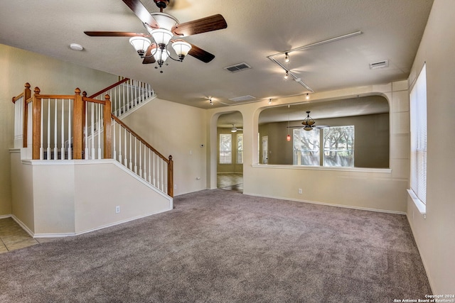 unfurnished room with light colored carpet, ceiling fan, track lighting, and a textured ceiling