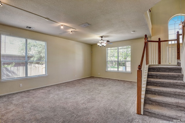 stairway featuring a textured ceiling, a wealth of natural light, ceiling fan, and track lighting