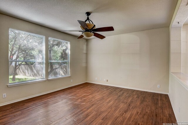 empty room with ceiling fan, dark hardwood / wood-style floors, and a textured ceiling