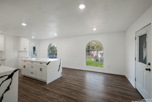 kitchen featuring a kitchen island, dark hardwood / wood-style floors, tasteful backsplash, and white cabinetry