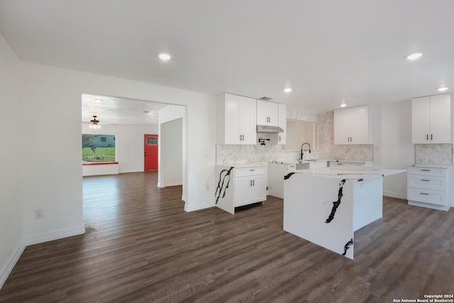 kitchen with white cabinets, tasteful backsplash, a kitchen island, and dark wood-type flooring