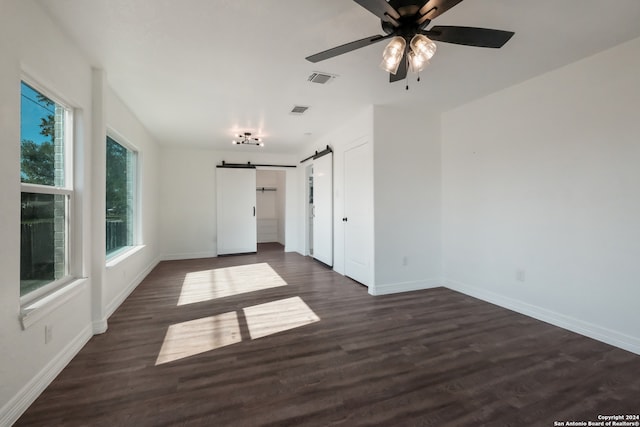 spare room featuring dark hardwood / wood-style flooring, ceiling fan, and a barn door