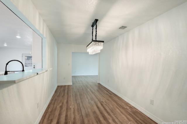 corridor with hardwood / wood-style floors and an inviting chandelier