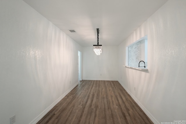 hall with a chandelier and dark wood-type flooring