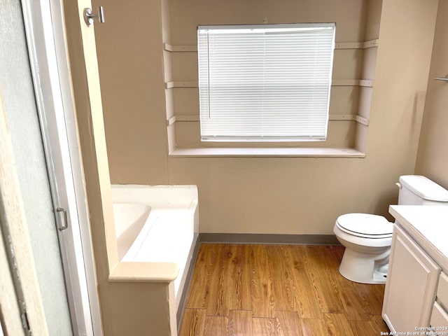 bathroom with toilet, vanity, hardwood / wood-style flooring, and a bathtub