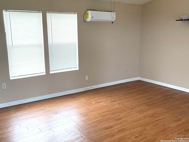 empty room with a wall mounted AC and light wood-type flooring