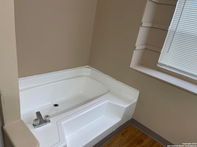 bathroom with a bath to relax in and wood-type flooring