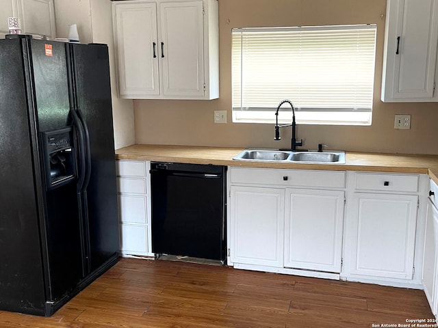 kitchen with sink, dark hardwood / wood-style flooring, white cabinetry, and black appliances