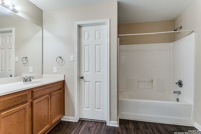 bathroom featuring wood-type flooring, a textured ceiling, shower / bathtub combination, and vanity