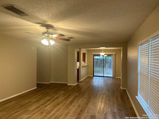 empty room with dark hardwood / wood-style flooring, ceiling fan, a wealth of natural light, and a textured ceiling