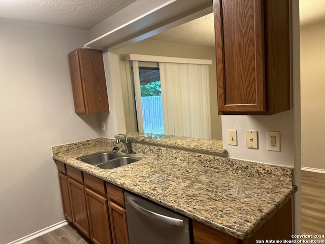 kitchen featuring sink, dark hardwood / wood-style flooring, stainless steel dishwasher, and light stone countertops