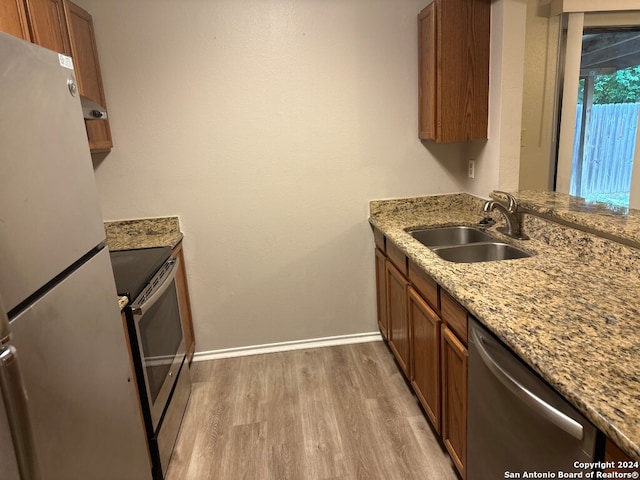 kitchen featuring wood-type flooring, stainless steel appliances, sink, and light stone countertops