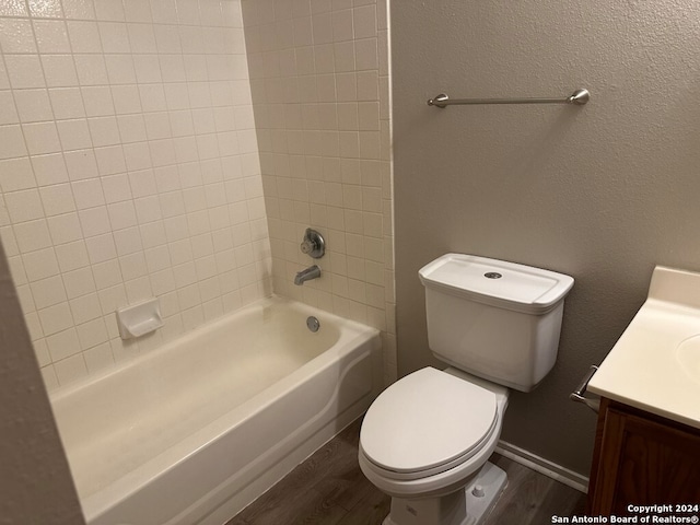 full bathroom featuring hardwood / wood-style floors, vanity, tiled shower / bath combo, and toilet