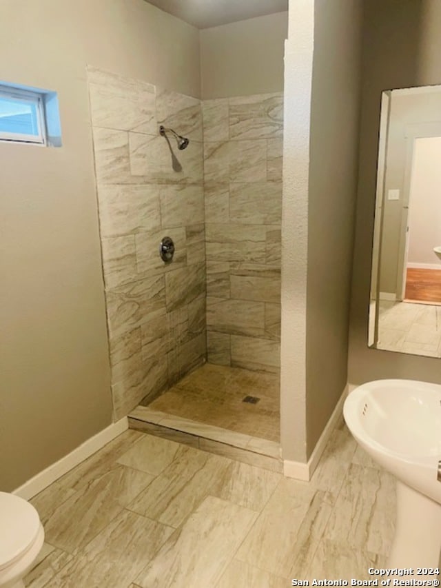 bathroom featuring a tile shower and toilet