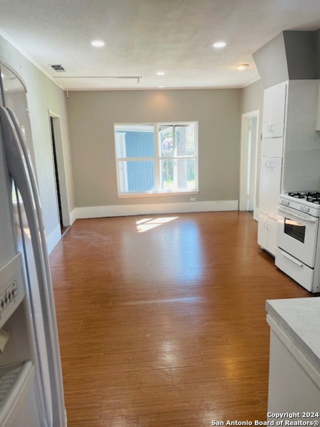 kitchen with light hardwood / wood-style flooring, white cabinets, and white gas stove