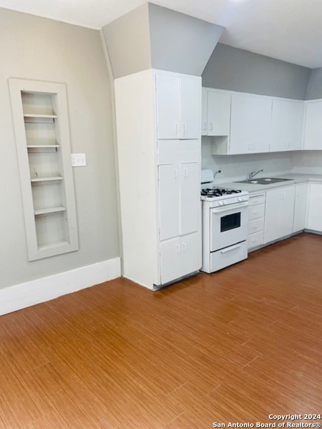 kitchen with sink, white cabinets, light hardwood / wood-style flooring, and white gas range