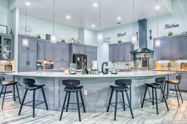 kitchen featuring wall chimney range hood, a breakfast bar, and a center island with sink