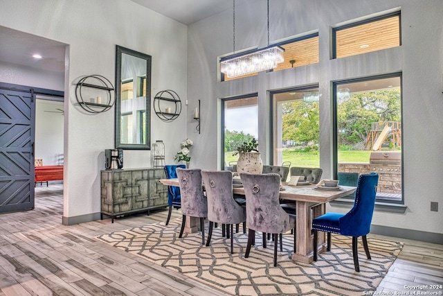 dining space featuring a chandelier, a barn door, and light hardwood / wood-style flooring