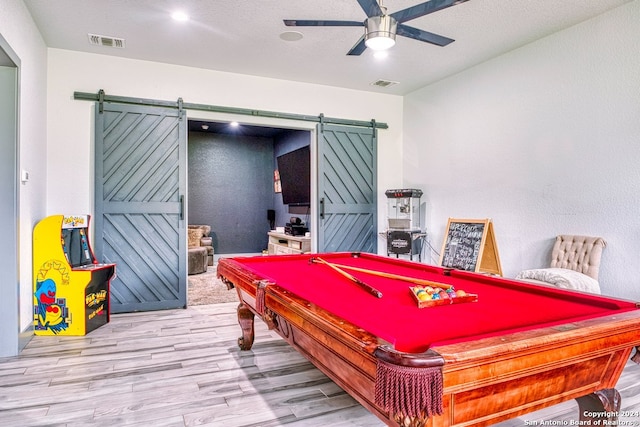 playroom featuring light hardwood / wood-style floors, ceiling fan, a barn door, and billiards