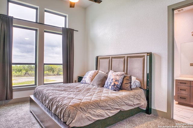 carpeted bedroom with ensuite bath and ceiling fan