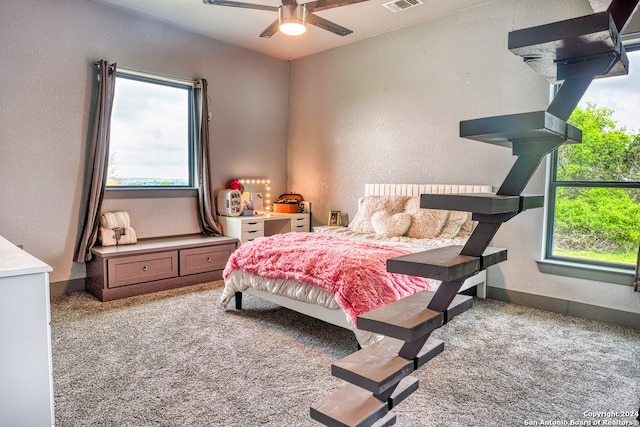 bedroom featuring light colored carpet, ceiling fan, and multiple windows