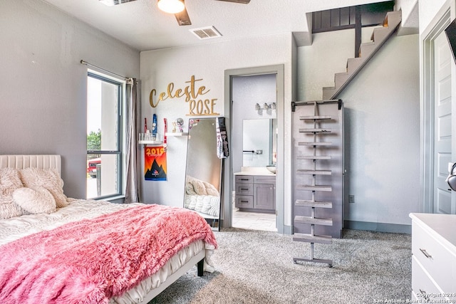 bedroom with light carpet, connected bathroom, ceiling fan, and a textured ceiling