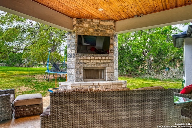 view of terrace with an outdoor stone fireplace and a trampoline