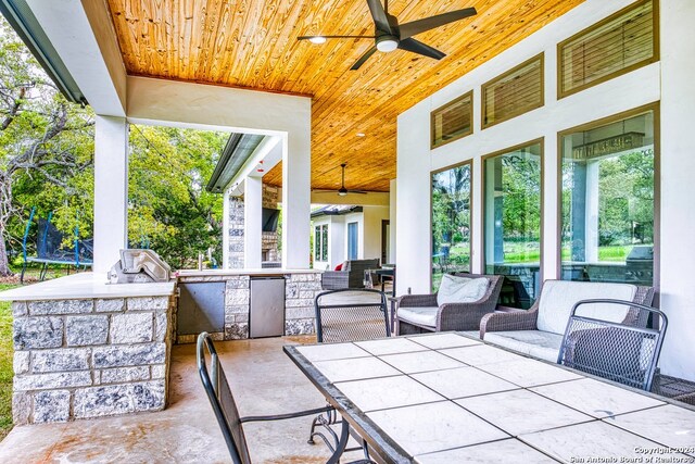 view of patio / terrace featuring area for grilling, ceiling fan, and an outdoor bar