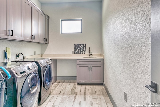 washroom featuring washer and clothes dryer, electric dryer hookup, sink, light hardwood / wood-style floors, and cabinets