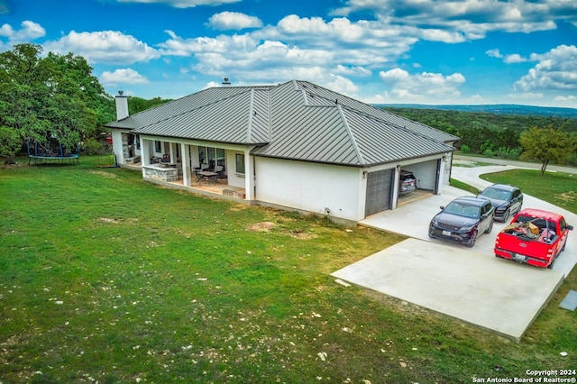 view of side of property with a trampoline, a garage, and a yard