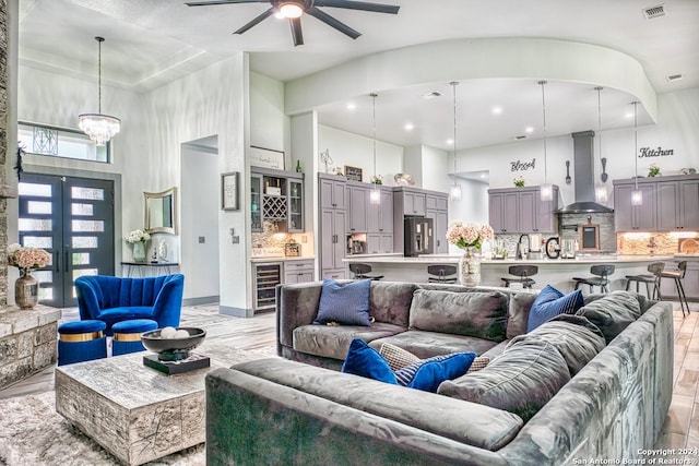 living room featuring ceiling fan with notable chandelier, sink, a towering ceiling, and beverage cooler