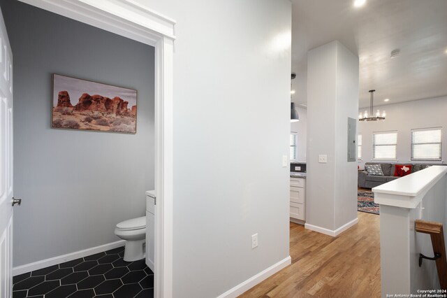 bathroom with hardwood / wood-style flooring, toilet, and a chandelier