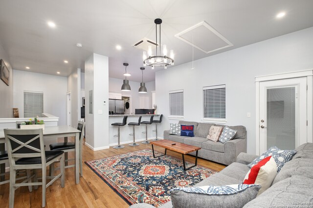 living room with light hardwood / wood-style floors and a notable chandelier