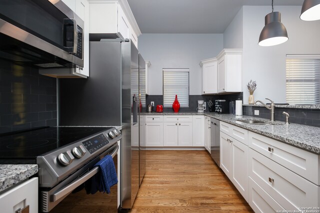 kitchen with light hardwood / wood-style floors, tasteful backsplash, white cabinetry, and stainless steel appliances