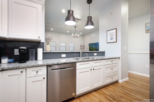 kitchen with backsplash, light wood-type flooring, white cabinetry, stainless steel dishwasher, and pendant lighting