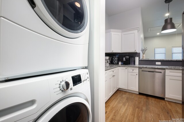 laundry room with light hardwood / wood-style floors and stacked washer and dryer