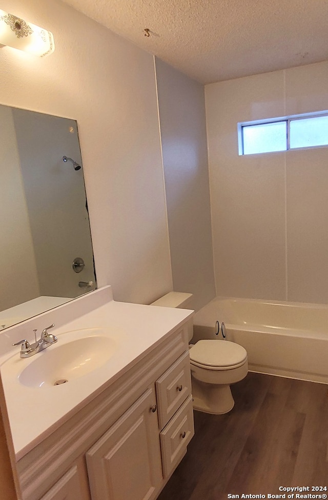 full bathroom with tub / shower combination, a textured ceiling, hardwood / wood-style floors, toilet, and vanity