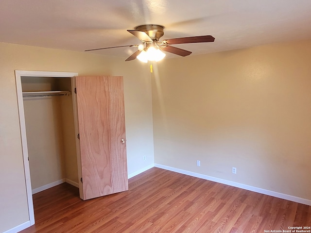 unfurnished bedroom featuring hardwood / wood-style flooring, a closet, and ceiling fan