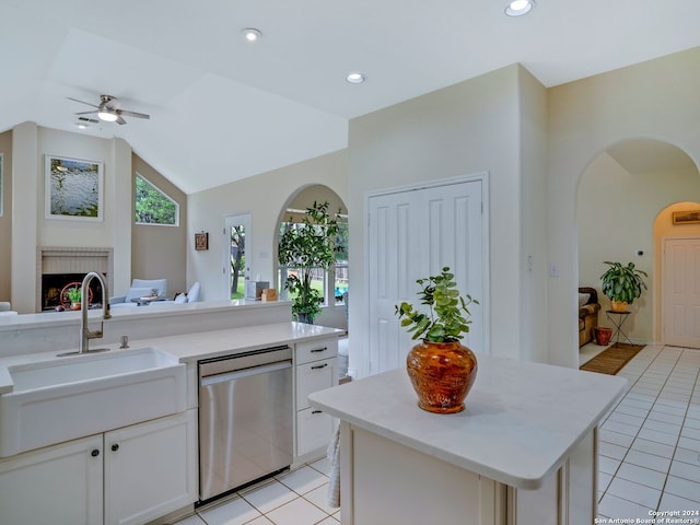 kitchen with ceiling fan, a brick fireplace, dishwasher, light tile flooring, and lofted ceiling