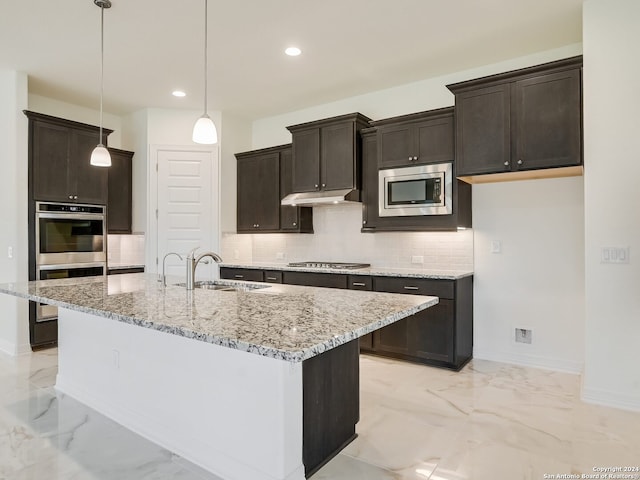 kitchen with appliances with stainless steel finishes, sink, backsplash, and a kitchen island with sink