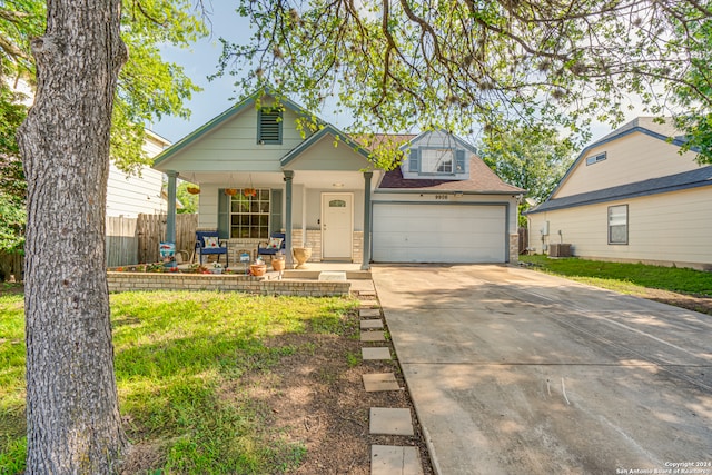 view of front facade featuring a front lawn, a porch, a garage, and central air condition unit