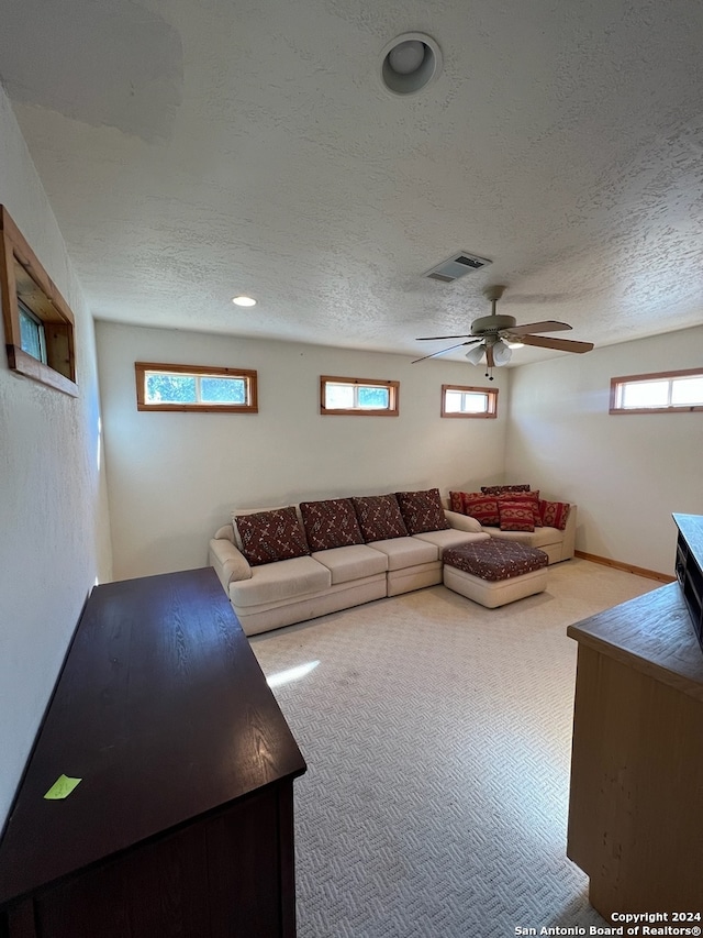 unfurnished living room with plenty of natural light, carpet, ceiling fan, and a textured ceiling