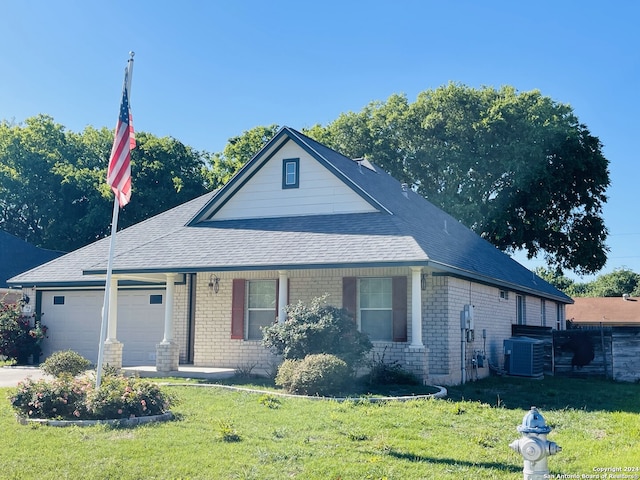 view of front facade featuring a garage, a front lawn, and central air condition unit