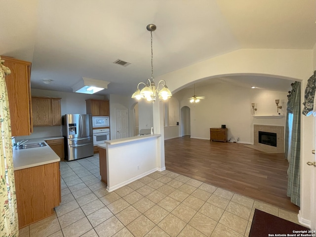 kitchen featuring decorative light fixtures, white appliances, vaulted ceiling, light tile floors, and a notable chandelier