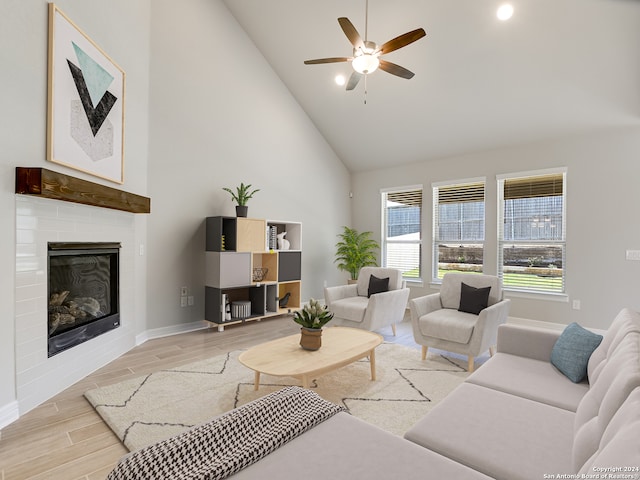 living room with high vaulted ceiling, light hardwood / wood-style floors, a brick fireplace, and ceiling fan