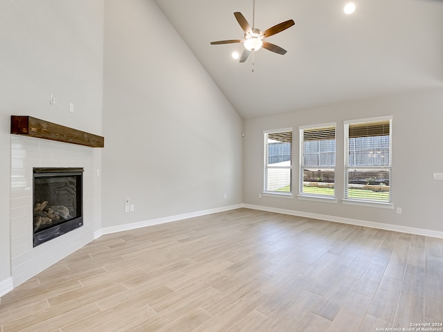 unfurnished living room featuring light hardwood / wood-style flooring, high vaulted ceiling, ceiling fan, and a brick fireplace