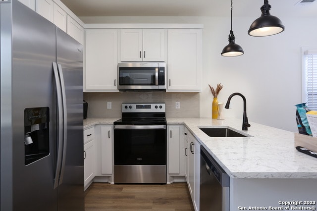 kitchen featuring decorative light fixtures, dark wood-type flooring, appliances with stainless steel finishes, sink, and tasteful backsplash