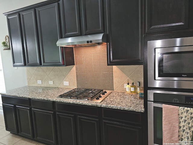 kitchen featuring tasteful backsplash, stainless steel appliances, light tile flooring, and light stone counters