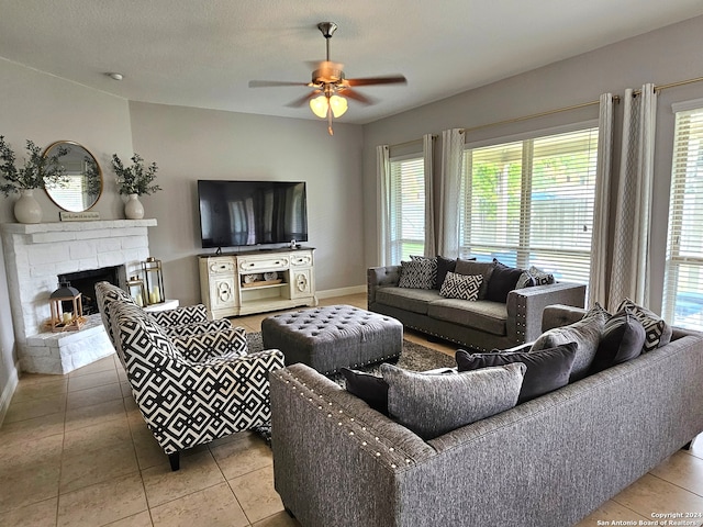 living room with a fireplace, ceiling fan, a textured ceiling, and tile flooring