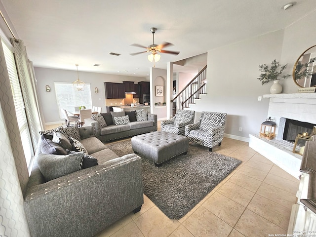 tiled living room with ceiling fan and a brick fireplace